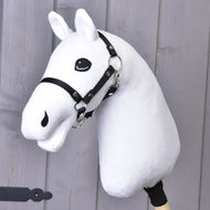 Zbuduj swojego konia, Hobby Horse od related_to_12441055625556 z pluszową białą głową, wyrazistymi niebieskimi oczami, czarnym ogłowiem i wodzami, osadzony na drewnianym kiju, pokazany przed jasnoszarą drewnianą ścianą.