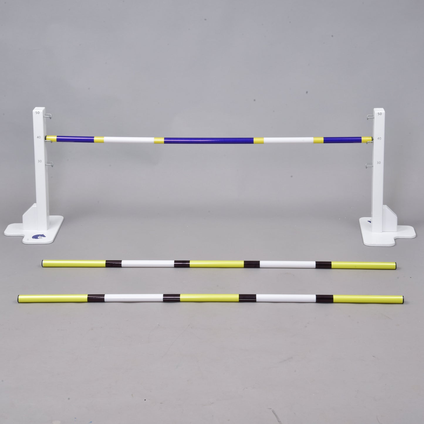 Przeszkoda 50 cm / 20 inch z dodatkowymi tyczkami od Hobby Horse LarDen zawiera trzy tyczki w paski — dwie na ziemi i jedną uniesioną — tworząc regulowaną przeszkodę do treningu jeździeckiego, dog agility lub Hobby Horsing, odpowiednią do użytku w pomieszczeniach lub na zewnątrz.