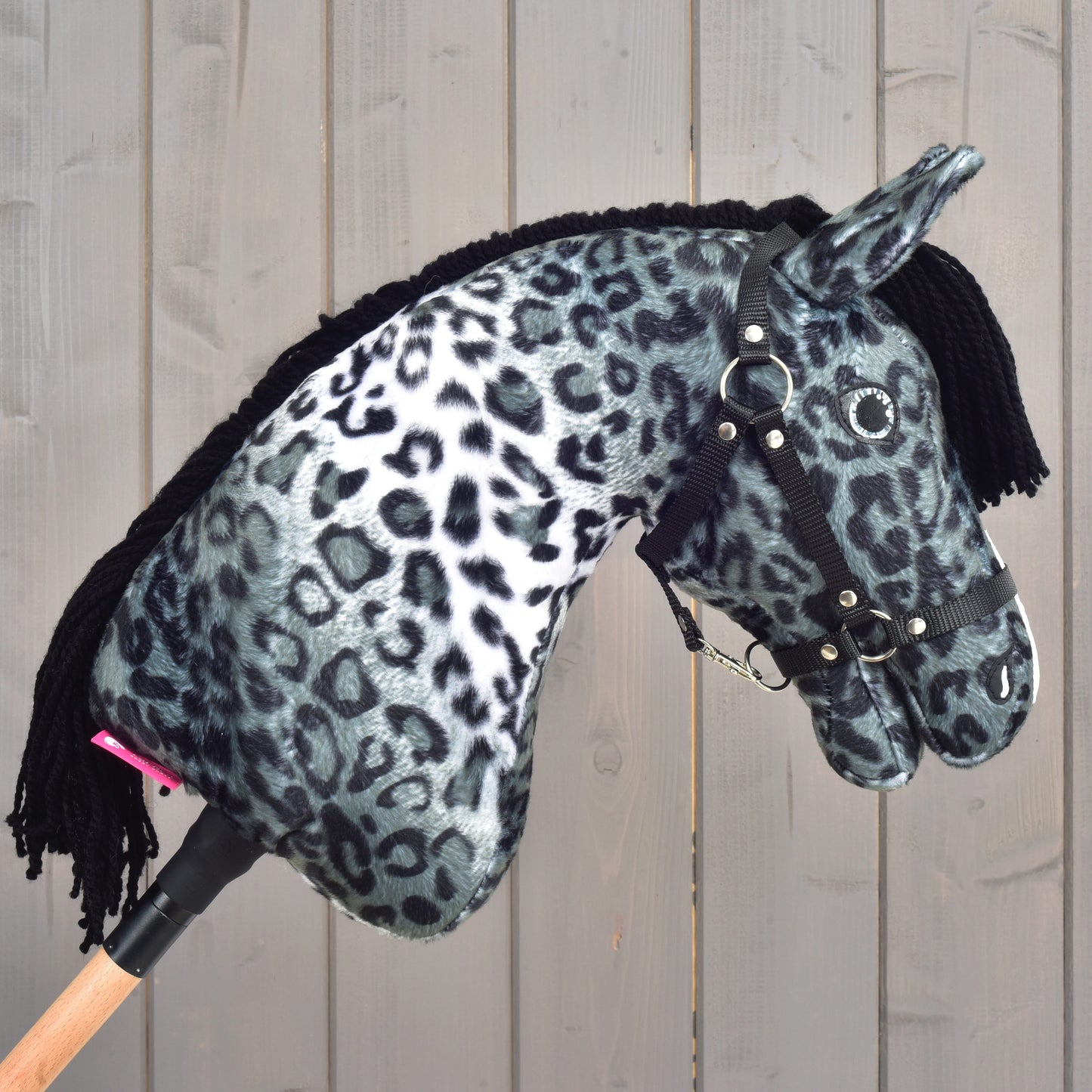 The Hobby Horse Picasso with Black Halter by Hobby Horse LarDen showcases a soft black and white leopard print pattern inspired by an Appaloosa’s spotted coat, complete with a black yarn mane and a black halter, displayed against a wooden background.