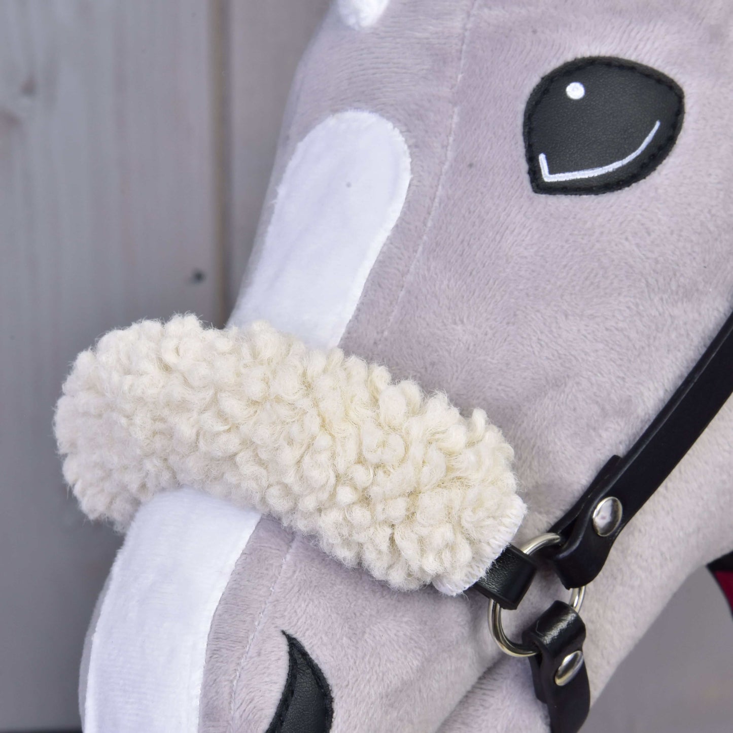 Close-up of the Set Harmony Victory by Hobby Horse LarDen, featuring a gray head with black and white accents, a white snout, and a fluffy cream noseband on a black halter.