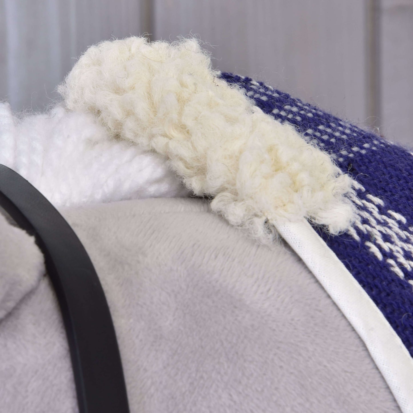 Close-up of the soft, cozy white fleece lining on the blue and white Set Harmony Victory stable blanket by Hobby Horse LarDen, shown with a gray surface and nearby black strap.